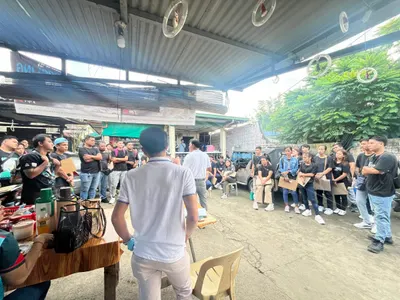 Workers gathered for an employee meeting under a steel roof