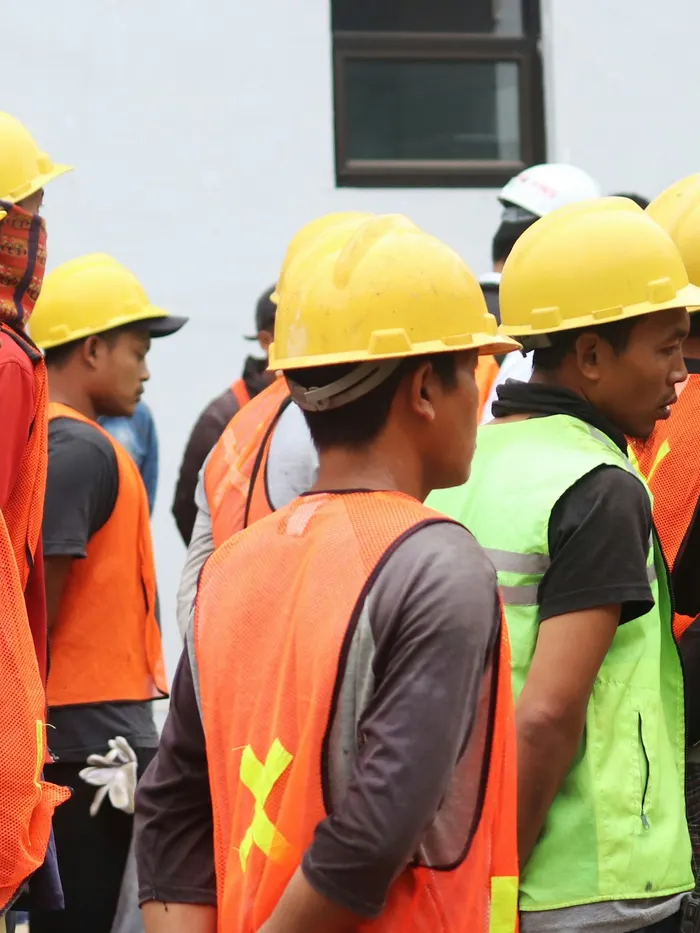 Workers in hard hats and safety vests lined up for a site briefing